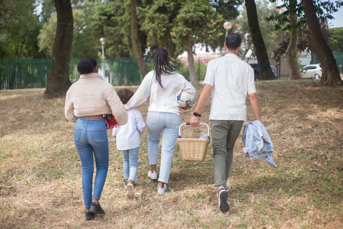A family walking together outdoors on a tree-lined path
